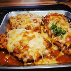 some meat covered in sauce and cheese on a pan with a fork next to it