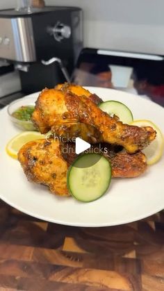 a white plate topped with chicken wings and cucumbers