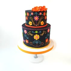 a three tiered cake decorated with flowers and beaded trims on a stand