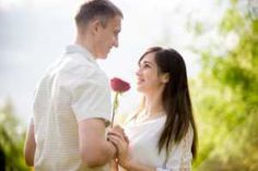 a man holding a rose next to a woman