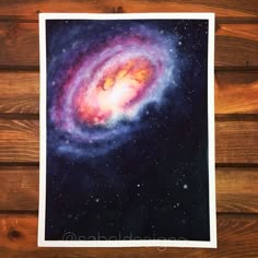 a painting of a spiral galaxy in purple and blue on a wooden wall with wood planks