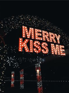 the merry kiss me sign is lit up at night