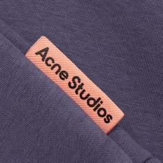 an orange label that says acne studios on the side of a purple shirt with black lettering