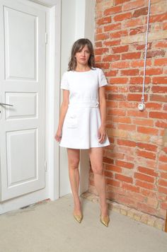 Step into timeless elegance with this vintage 80s white short sleeve dress. Featuring a flared silhouette that flatters the figure, this dress is adorned with subtle embellishments that add a touch of sparkle and sophistication. The convenient pocket adds a practical yet stylish detail, making this dress both beautiful and functional. Sized small, it offers a comfortable fit perfect for various occasions. In excellent vintage condition, this dress captures the classic charm and understated glamo White Fitted Mini Dress With Cap Sleeves, Fitted White Mini Dress With Cap Sleeves, White Short Sleeve Mini Dress For Work, White Short Sleeve Mini Dress For Formal Occasions, White Fitted Knee-length Short Sleeve Dress, White Vintage A-line Mini Dress, White Short Sleeve Dress, 80s Fashion, White Short