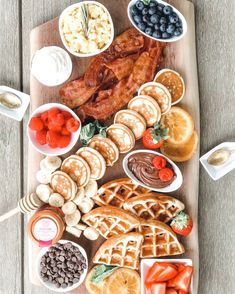 a wooden tray topped with waffles, fruit and other foods