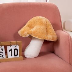 a stuffed mushroom hat sitting on top of a pink chair next to a calendar with the number ten