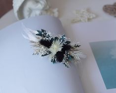 an open book with flowers and feathers on it