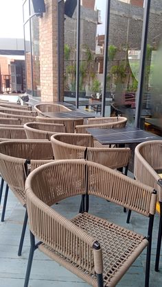 many chairs and tables are lined up on the sidewalk outside an outdoor dining area with large windows