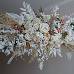 an arrangement of flowers and feathers hanging from the ceiling