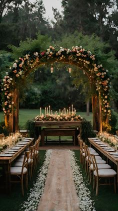 an outdoor wedding setup with flowers and candles on the table, surrounded by greenery