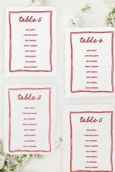 three place cards with red ink on them and white flowers in the backgroun