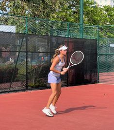 a woman holding a tennis racquet on top of a tennis court