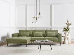 a living room with a green couch and two vases on the floor next to it