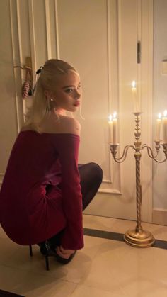 a woman sitting on the floor next to a candelabra