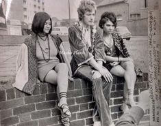 three young women sitting on top of a brick wall