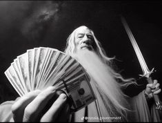 a man with long white hair and beard holding a fan of money in his hand