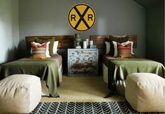 two beds in a room with green blankets and pillows on them, one has a railroad crossing sign above the headboard