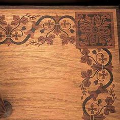 a cat sitting on top of a wooden floor next to a rug with flowers and vines