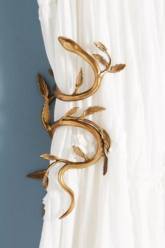 a curtain rod with gold leaves hanging on it's side in front of a blue wall