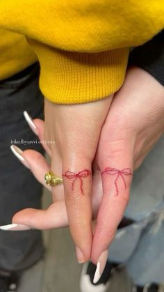 two people holding hands with tattoos on their fingers