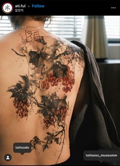 the back of a woman's tattoo with grapes on it