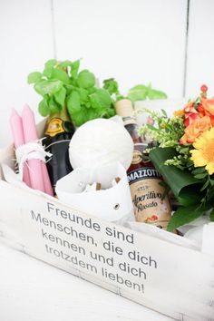 an arrangement of flowers in a wooden box on a white table with a sign that says, freunde sin menschen, die ditch