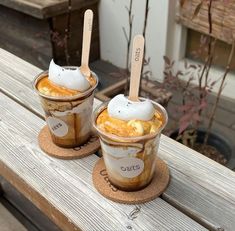 two ice cream sundaes sitting on top of a wooden table next to each other