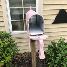 a pink mailbox sitting on top of a wooden post