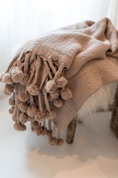 a brown blanket sitting on top of a wooden bench next to a basket and window