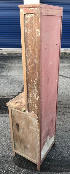 an old pink refrigerator sitting on top of a wooden box next to a blue wall