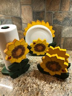 three sunflowers sitting on top of a counter next to a roll of toilet paper