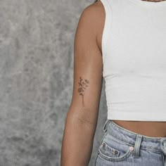 a woman with a flower tattoo on her left arm and right arm behind her back