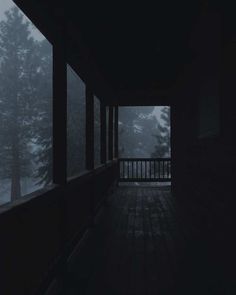 an empty porch in the middle of a dark forest at night with fog coming from the trees