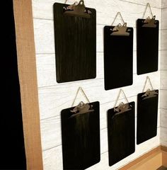 four black clipboards hanging on a white wall