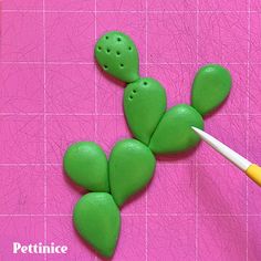 a green plant with holes in the middle and a yellow marker next to it on a pink surface