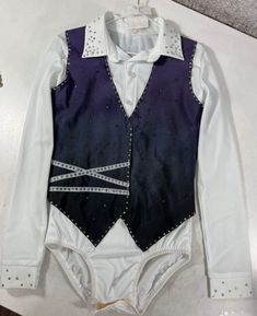 a white shirt and black vest with silver studdings on the chest, attached to a hanger