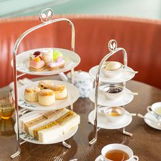 three tiered trays filled with pastries and tea on top of a wooden table