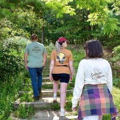 three people walking up some steps in the woods