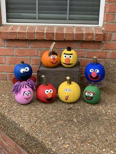 pumpkins painted to look like cartoon characters sitting in front of a brick building with windows