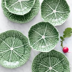 four green plates with leaf designs on them