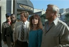 a group of men and women standing in front of a business building with one woman looking at the camera