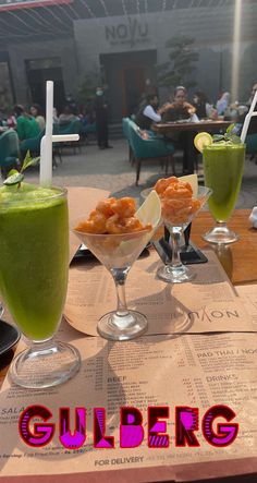 three glasses filled with drinks sitting on top of a table next to eachother