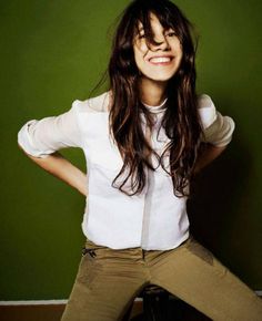 a woman with long hair is posing for a magazine cover shot, wearing khaki pants and a white shirt