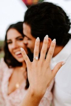 a man and woman are holding their hands up to show the engagement ring on their finger