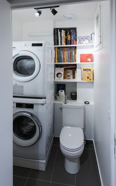 a washer and dryer in a small room with books on the shelves above