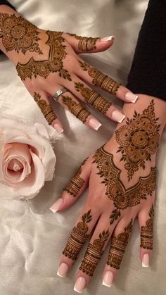 two hands with henna tattoos on them and a rose next to it, all decorated in gold