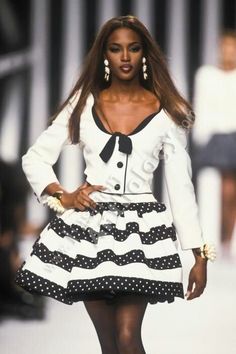 a woman is walking down the runway wearing a skirt and jacket with polka dots on it