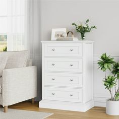 a white chest of drawers next to a couch and potted plant in a living room