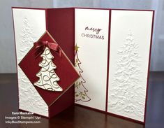 an open christmas card with a tree on the front and bottom, sitting on a table