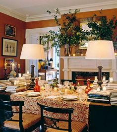 a dining room table set for dinner with candles and books on the table in front of it